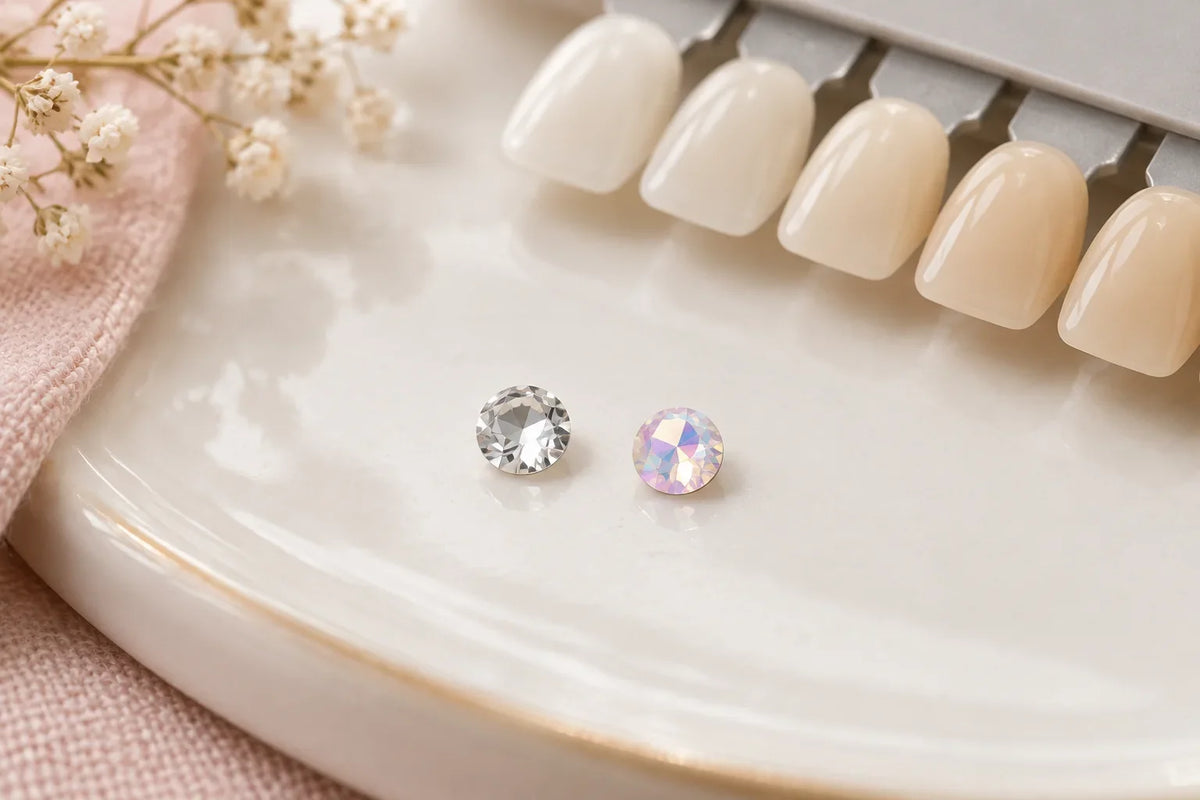 Clear Crystal and iridescent Crystal AB tooth gems side by side on a dental shade guide